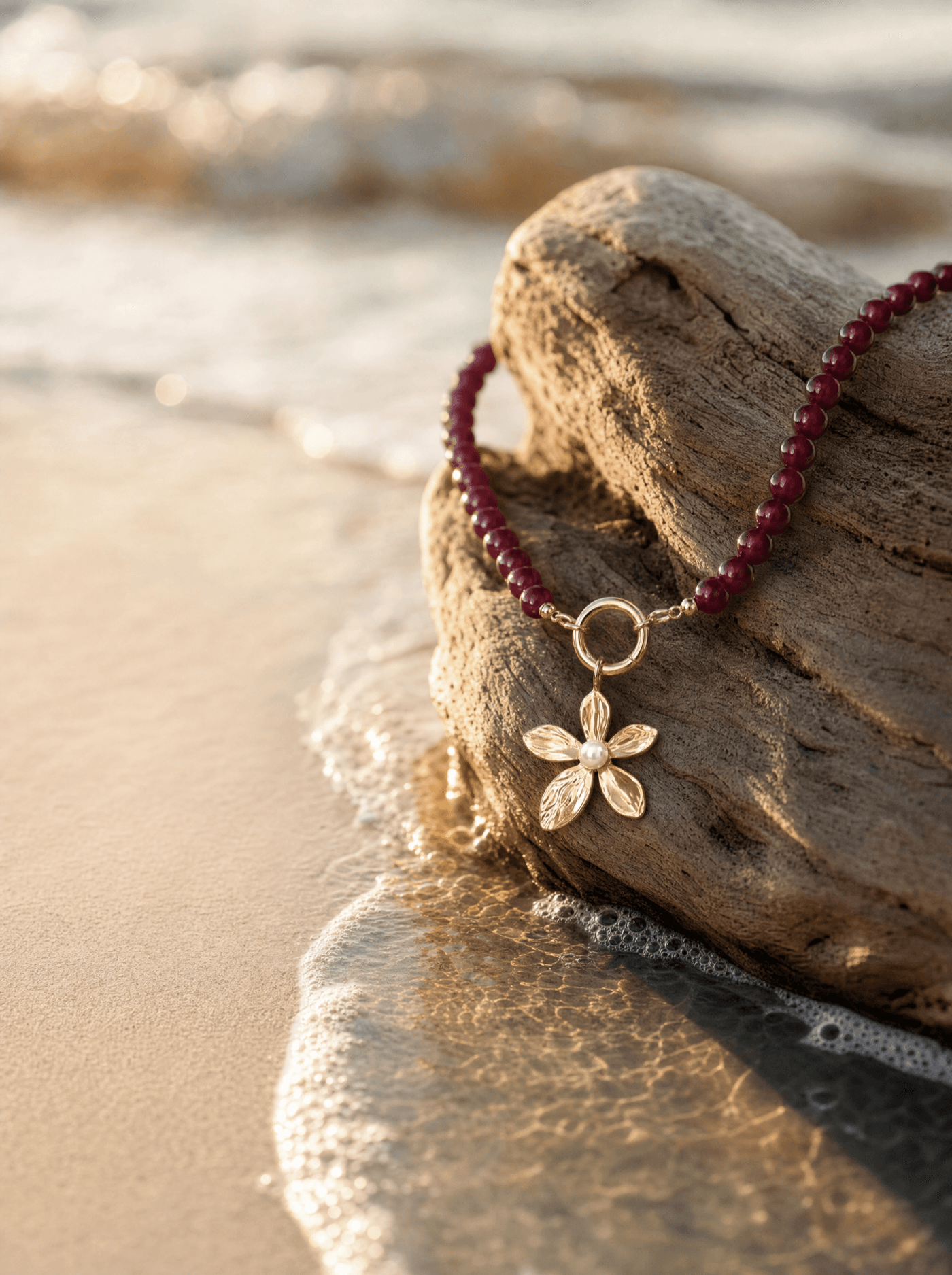 Collar de ágata roja sobre madera de deriva a la orilla del mar al atardecer.