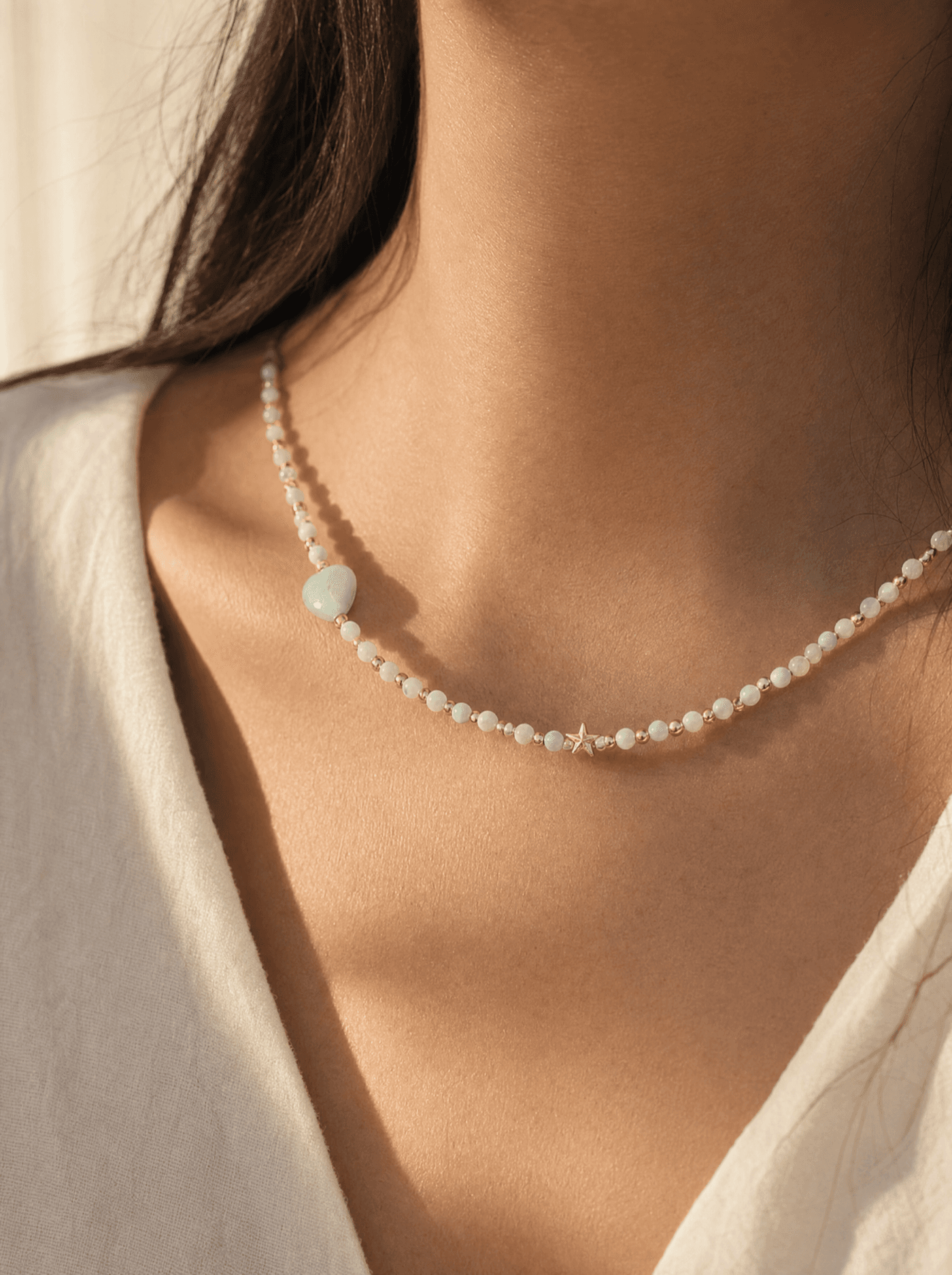 Gargantilla de cuentas de amazonita verde pálido con dije de gota verde sobre cuello de mujer.